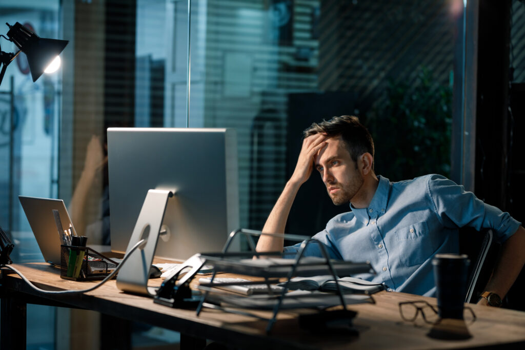 Man sitting alone in office late at night watching computer and solving problem, working overtime